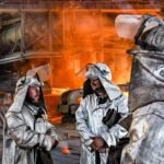 Workers in safety gear inside an industrial steel factory