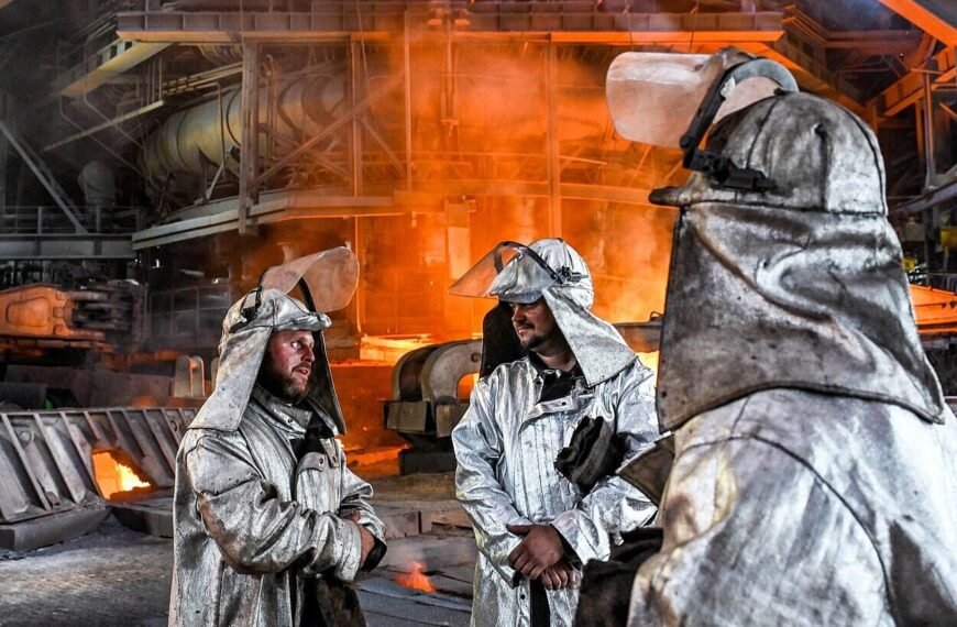 Workers in safety gear inside an industrial steel factory