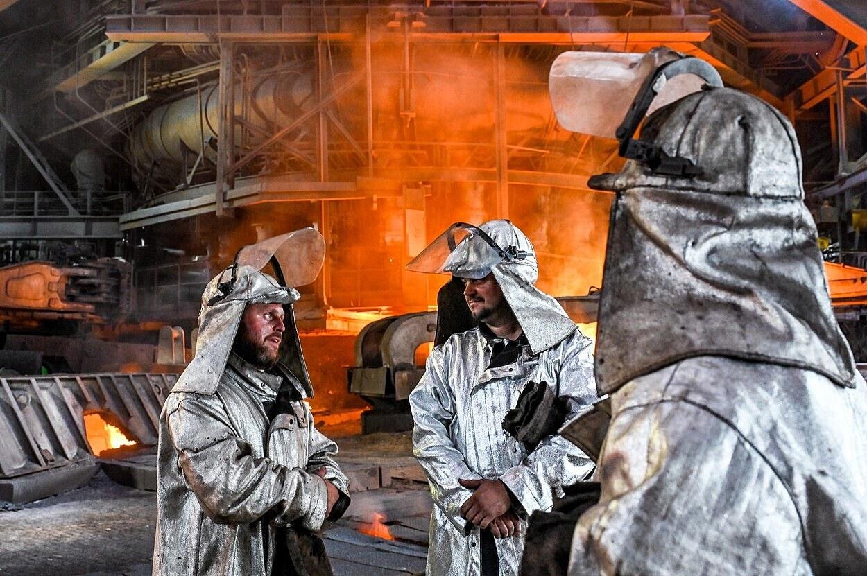 Workers in safety gear inside an industrial steel factory